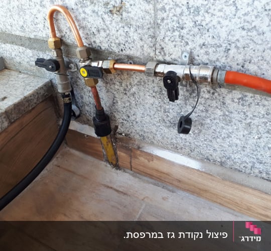 צינורות גז עם ברזים ומחברים על קיר אבן